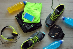 traveling shoes, green tshirt, energy drinks bottle, headphone , mobile phone on a floor