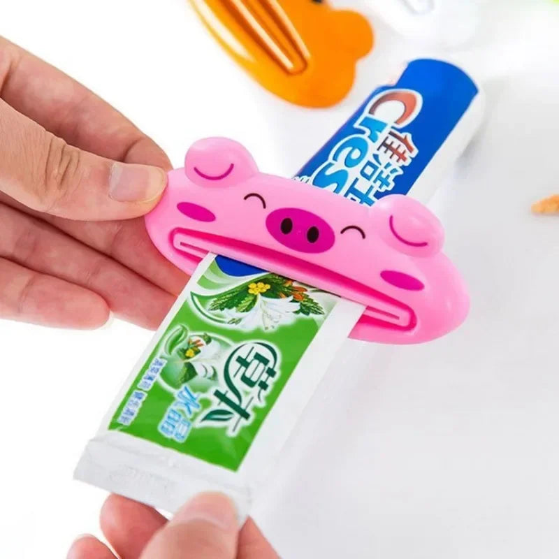 Pink cartoon rolling toothpaste squeezer dispenser by Lamp Post, a fun kid's bathroom tool for easy toothpaste tube squeezing.