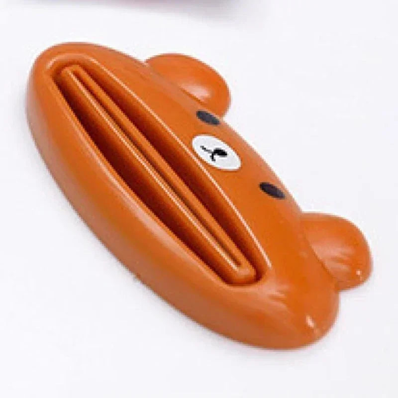 Pink cartoon rolling toothpaste squeezer dispenser by Lamp Post, a fun kid's bathroom tool for easy toothpaste tube squeezing.