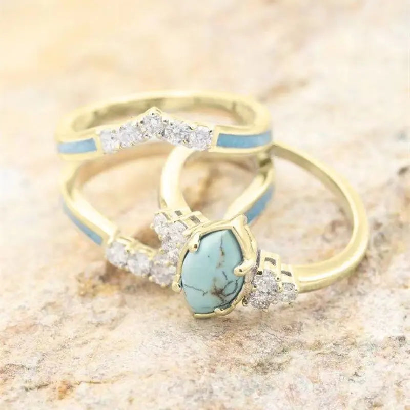 Women’s green stone ring set by Lamp Post featuring multiple gold-tone rings with vibrant green gemstones.