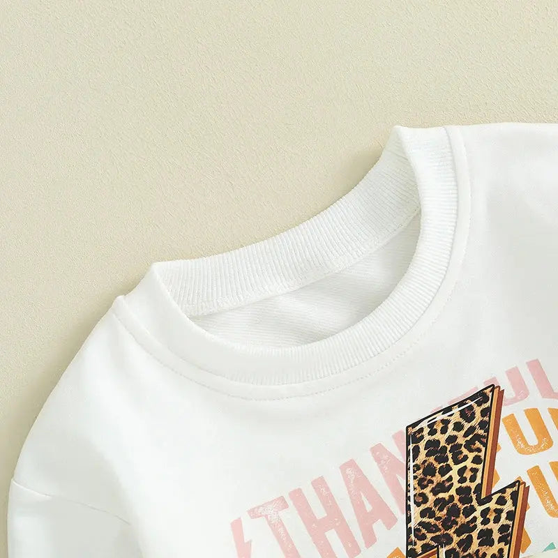 Baby girl or boy Thanksgiving outfit by Lamp Post, featuring a white long sleeve T-shirt, crewneck sweatshirt, and long pants.