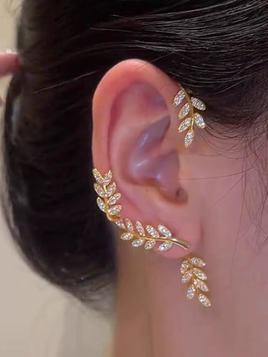 Gold female stud earrings with leaf design from Lamp Post, hanging on a woman's left ear, stylish and elegant jewelry.