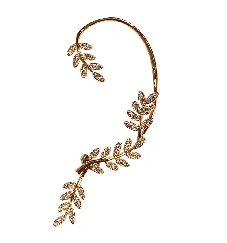 Gold female stud earrings with leaf design, hanging from a woman's left ear, by Lamp Post, stylish and elegant ear jewelry.
