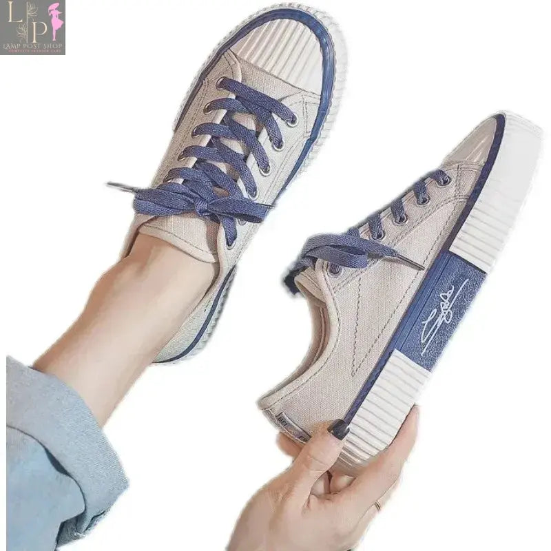 White low-top canvas women's sneakers with lace-up design, flat casual style, breathable fabric, and vulcanized outsole.