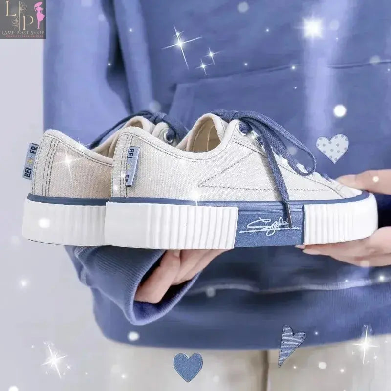White low-top canvas women's sneakers with lace-up closure, flat casual design, breathable fabric, vulcanized sole, soft and comfortable.