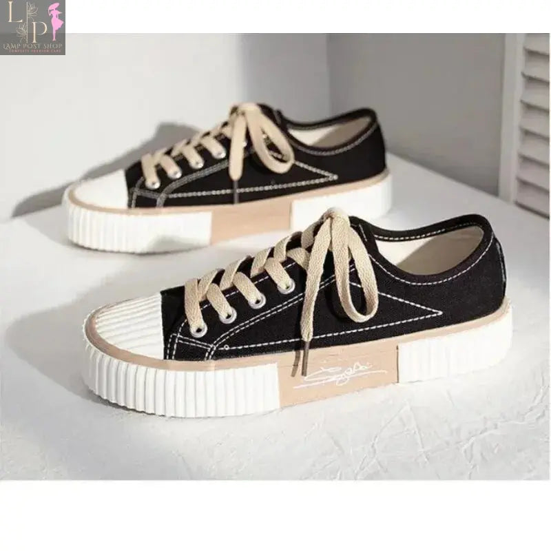 White low-top canvas women's sneakers with lace-up design, flat casual style, breathable fabric, and vulcanized rubber sole.