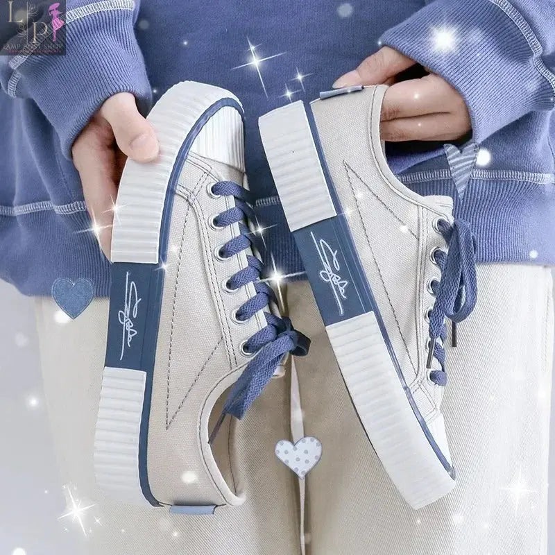 White low-top canvas women's sneakers with lace-up design, flat casual style, breathable fabric, and vulcanized rubber sole.